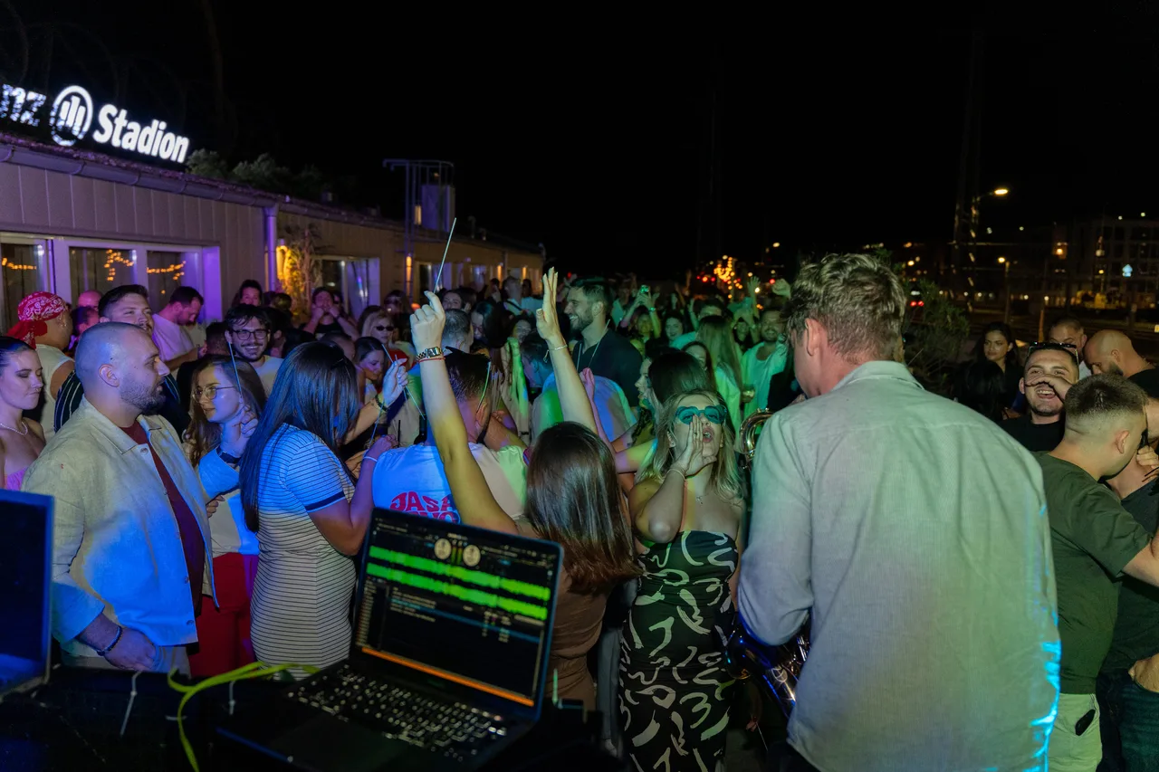 Seen from the DJ booth: a terrace party in Vienna, hands in the air, the crowd turned toward Jovan Pastar and his saxophone