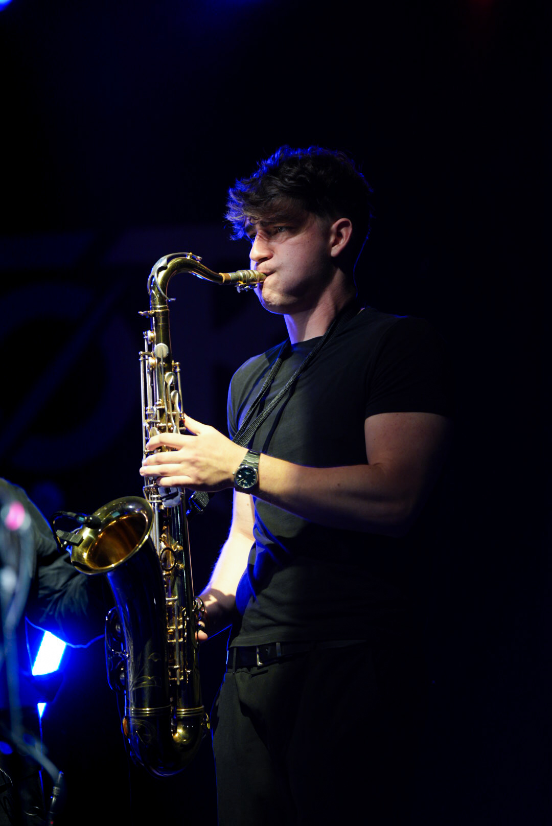 Jovan Pastar playing saxophone under blue stage light