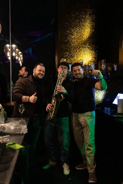 Jovan Pastar at the bar between sets with two guests, glitter still in the air