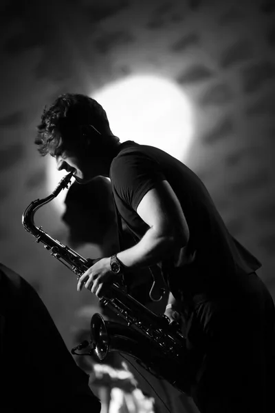 Jovan Pastar mid-phrase on the saxophone, in black and white