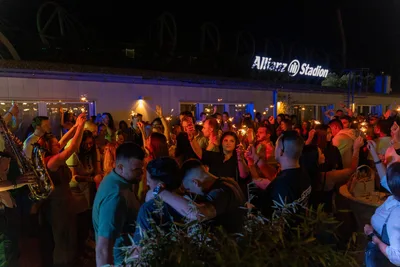 Sparklers held up across a packed terrace, the saxophone at the edge of the crowd